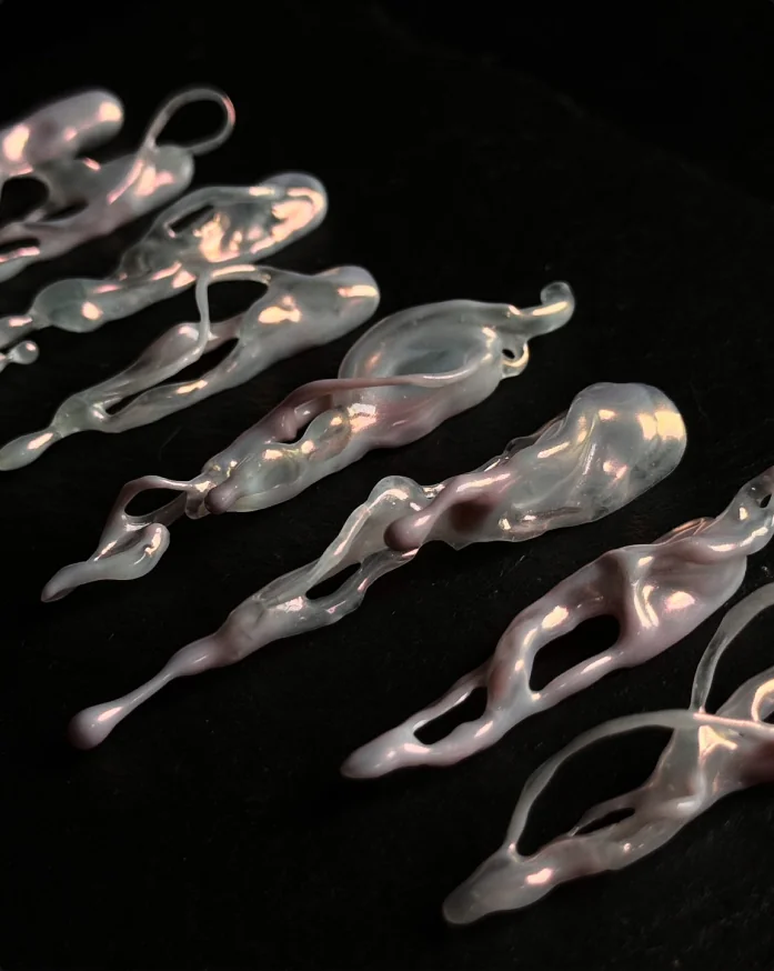 Pearlescent hand-formed claw objects laid out on black slate
